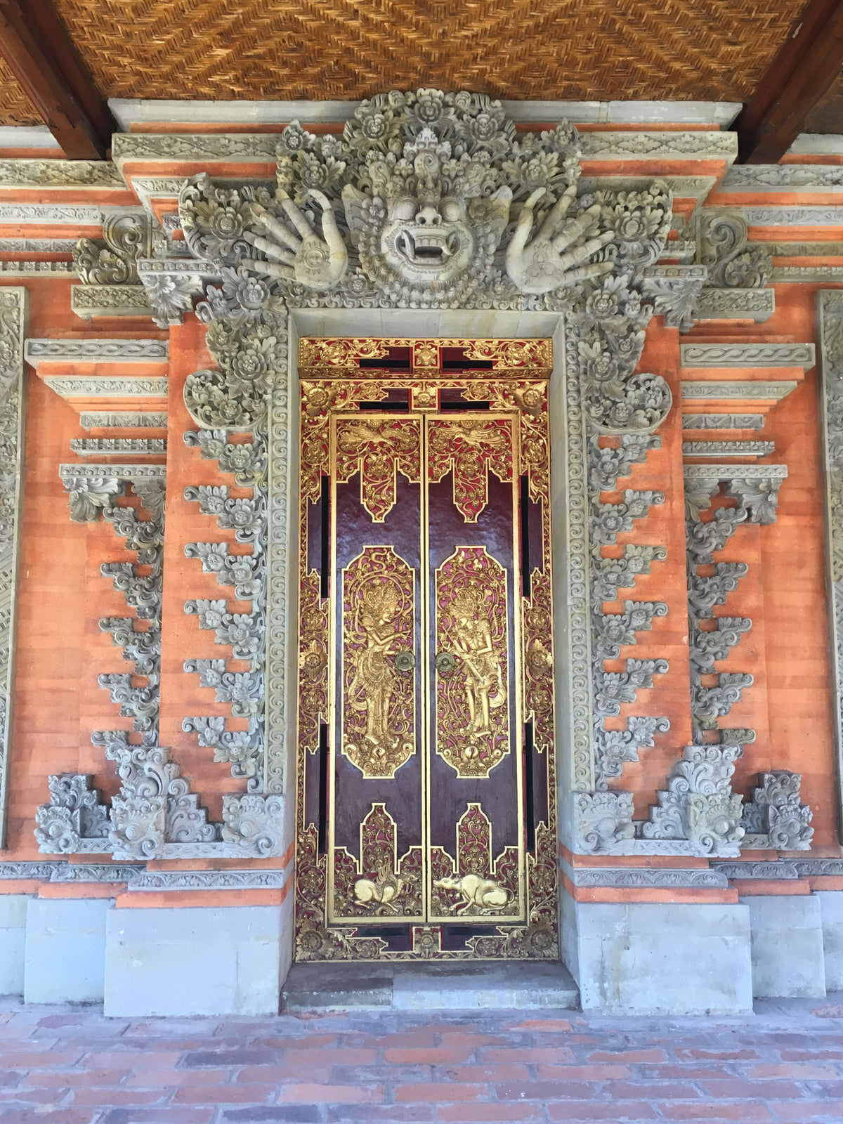 朱色の煉瓦と石彫りに囲まれた金と紫の扉
